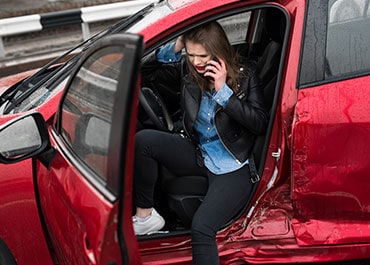 A woman sitting casually in the open door of a car, representing a personal injury case - Pezzano Law Group