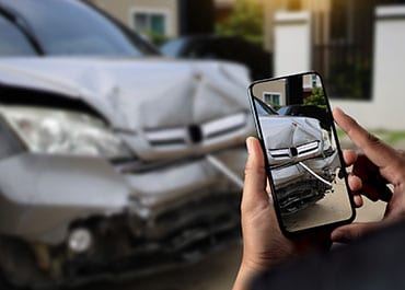 A person taking a photo of a damaged car front after an accident for personal injury evidence. 